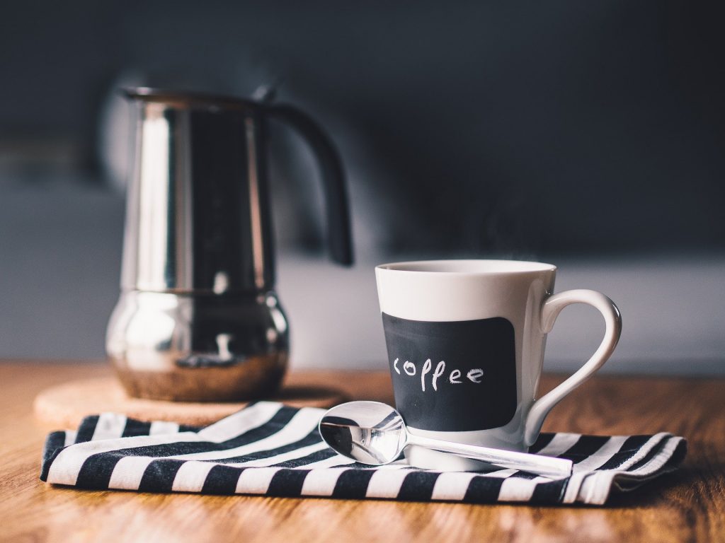 Tasse à café posée sur une serviette de table à coté d'une petite cuillère