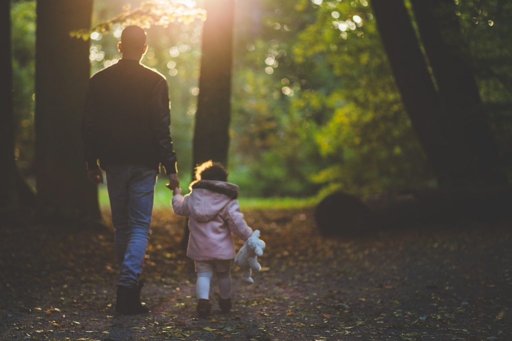 un père et sa petite fille en balade dans une forêt