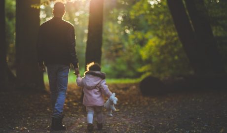 un père et sa petite fille en balade dans une forêt