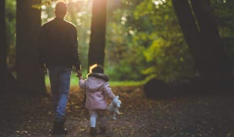 un père et sa petite fille en balade dans une forêt