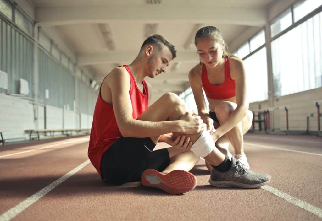 personne qui fait un bandage à un sportif